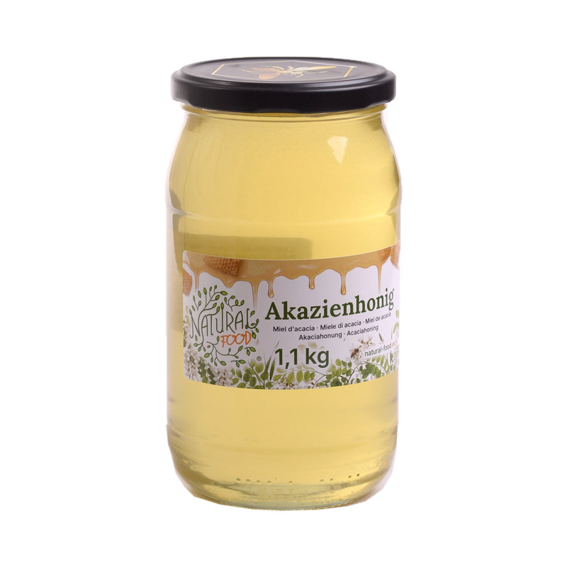 Miele di acacia Natural-Food in vasetto da 1,1 kg con la nuova etichetta, miele chiaro e liquido su sfondo bianco